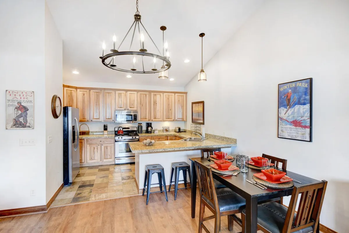 An open-concept kitchen and dining area, where a central kitchen island flows naturally into a spacious dining table set for a meal. The space is decorated with wall-mounted artwork, and soft lighting creates a welcoming mood for sharing recipes, celebrating special occasions, and making memories over meals.