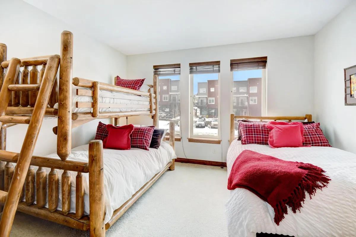 A cozy bunk bedroom with inviting bedding and a large window letting in gentle light. The intimate scale and warmth of the space evoke comfort and family togetherness, perfect for children or extra guests.