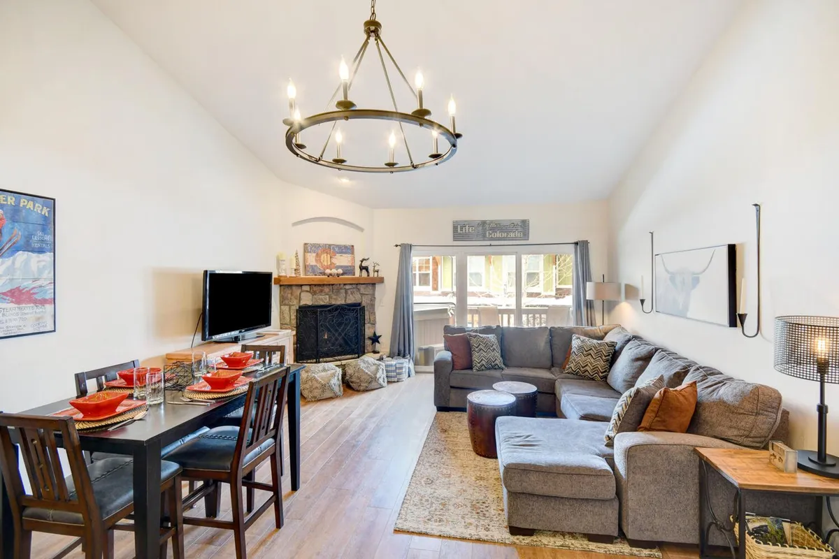 An inviting living and dining area with a comfortable sectional sofa, a fireplace, and a dining table set for family meals. The space feels warm and welcoming, ideal for sharing stories or relaxing after outdoor adventures.