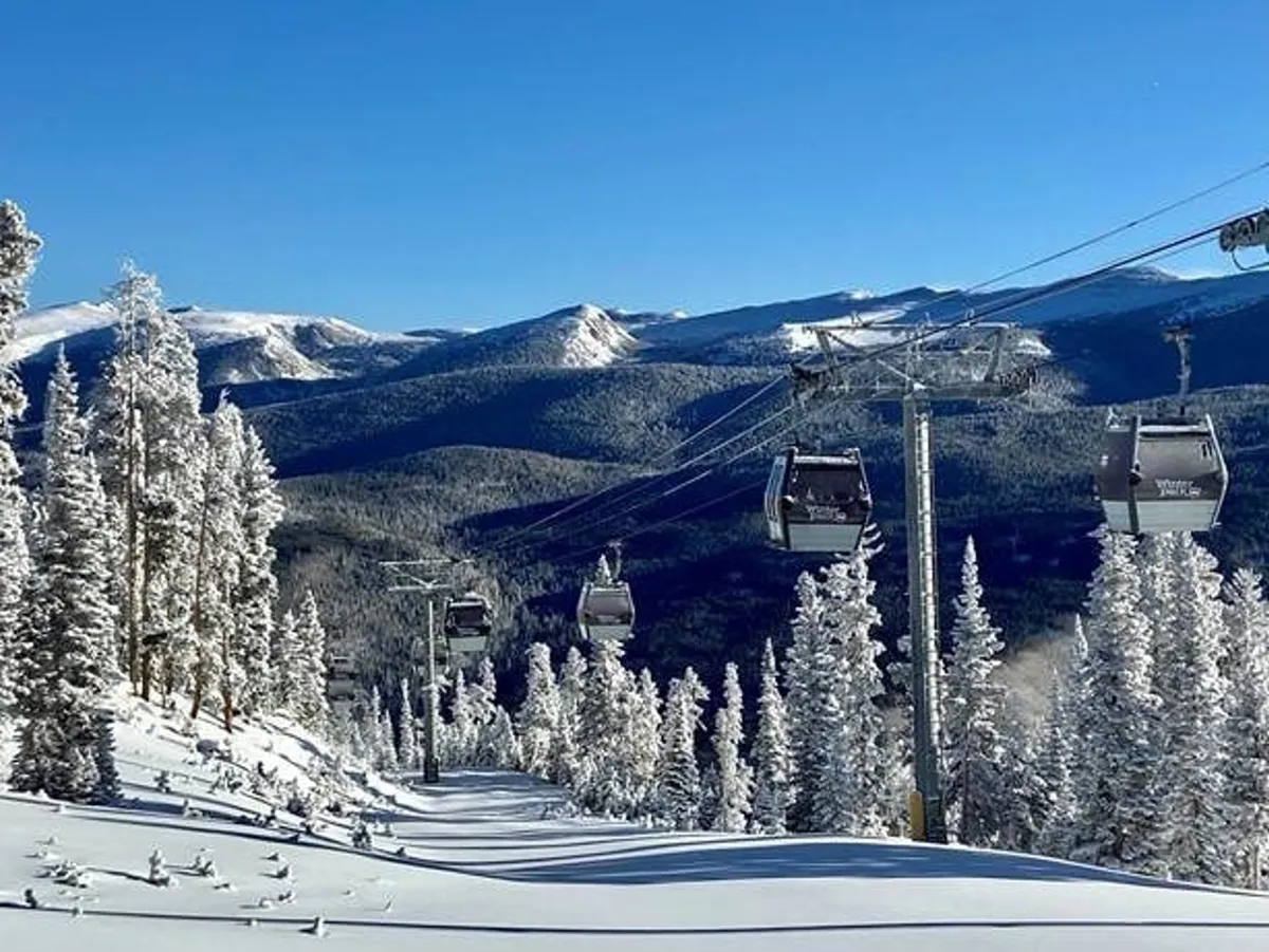 An exterior shot capturing a ski lift ascending snow-covered mountains, surrounded by evergreen trees. The crisp winter landscape sets a sense of adventure and tranquil beauty, hinting at world-class skiing and snowboarding just minutes away.